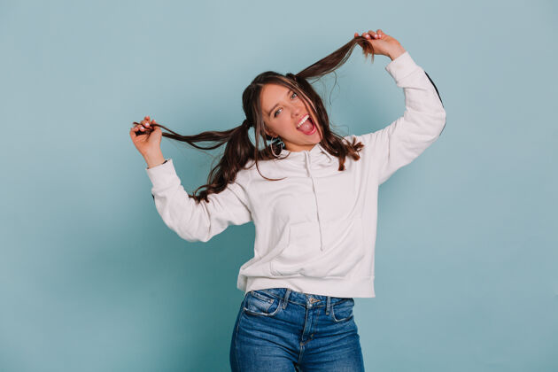 青少年滑稽可笑的女人玩她的头发做的脸 并在孤立的墙上跳舞Spa青少年表情