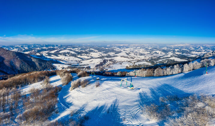 山谷鸟瞰美丽的冬季山坡覆盖着雪和冷杉森林在晴朗无云的日子欧洲滑雪胜地美丽的概念山雪娱乐