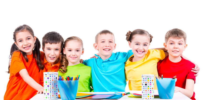 同学一群孩子坐在桌子旁 手里拿着记号笔 蜡笔和彩色纸板小教育孩子