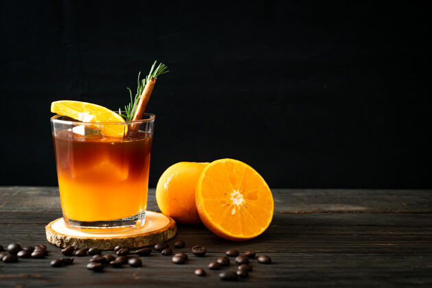 刷新一杯冰美式黑咖啡和一层用迷迭香和肉桂装饰的橙汁和柠檬汁果汁咖啡杯黑色