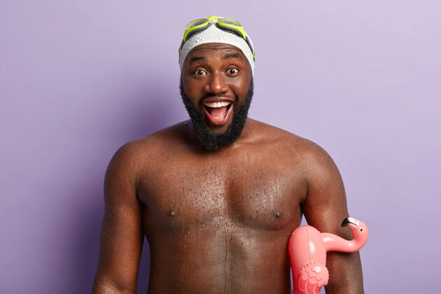裸露快乐的非洲裔美国男人的头像在度假地度过休闲时光 在海或海洋中学习游泳后有美好的印象 拿着橡皮圈 表达积极的情绪和感受情绪潮湿健美运动员