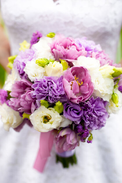 花特写镜头美丽的新娘手持新娘花束与白色 粉红色和紫色的花朵新娘新郎花店