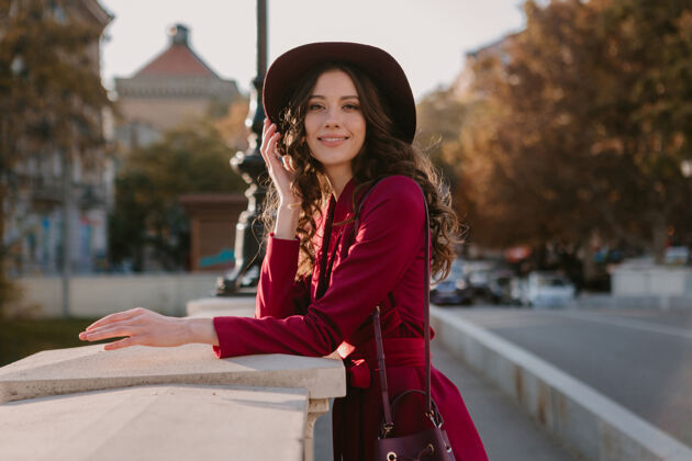 女人靓丽时尚的紫衣女人走在城市的大街上 春夏秋冬时节时尚潮流戴着帽子 拿着钱包套装阳光漂亮