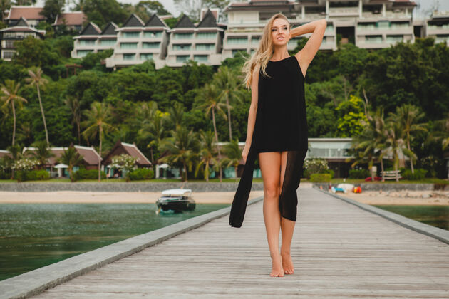 热带美丽迷人的女人穿着浪漫的黑色礼服摆在码头上的豪华度假酒店 女孩岛屿无忧无虑