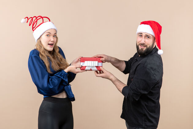 礼物年轻女子和送她礼物的男人在粉红色墙上的正视图模特成人圣诞快乐