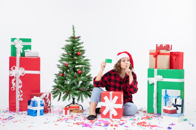 雪正面图：年轻女子围坐在白墙上 手里拿着绿色的银行卡圣诞快乐快乐抱着
