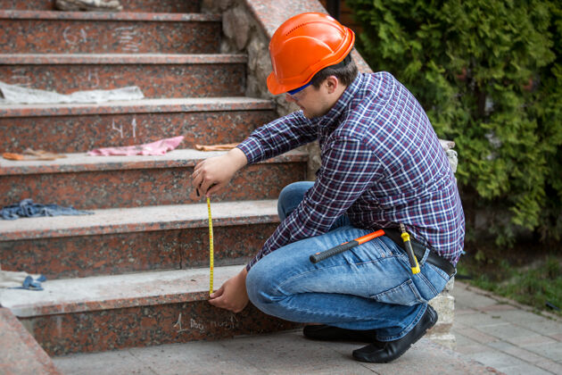 测量年轻的建筑工人用卷尺测量楼梯高度实际改善墙