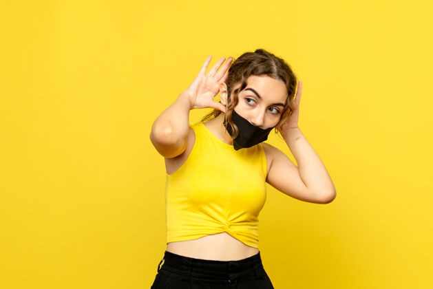 不育黄色墙壁上戴着无菌口罩的年轻女孩的正视图年轻女孩人流行
