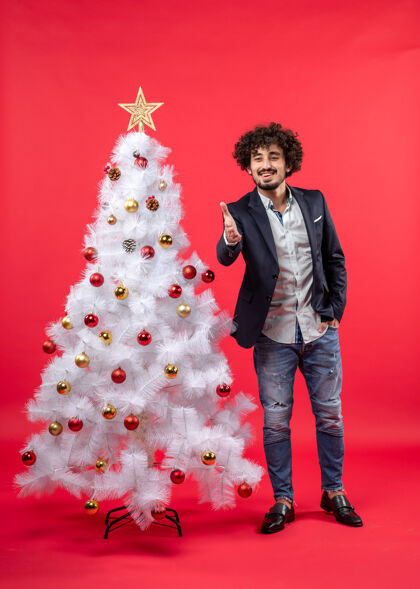 配件圣诞节庆祝与快乐有趣的年轻人欢迎某人站在圣诞树附近与配件快乐装饰微笑