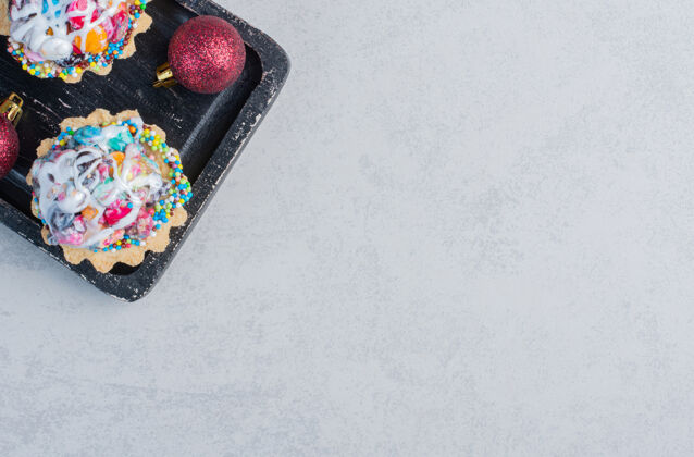 小吃在大理石表面的黑色托盘里放着圣诞饰品和糖果蛋糕甜点美味糖果