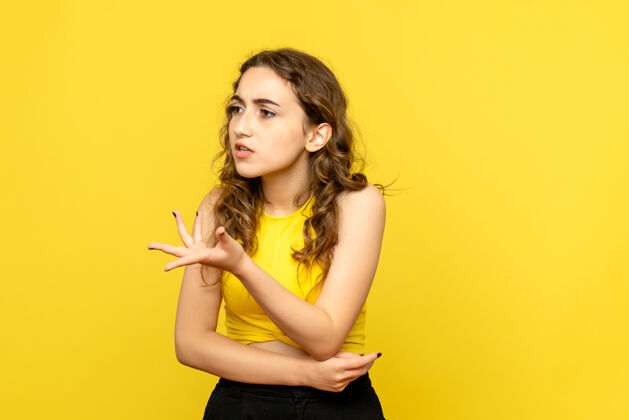 模特年轻女子在黄色墙壁上争吵的正面图年轻争论漂亮