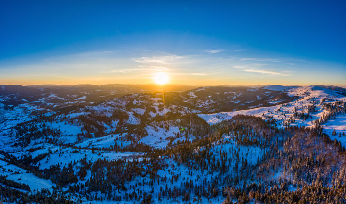 日落如诗如画的冬季全景 在阳光明媚 天空湛蓝的日子里 雪山和冷杉树覆盖着群山原始的自然美景概念空间冰川寒冷雪