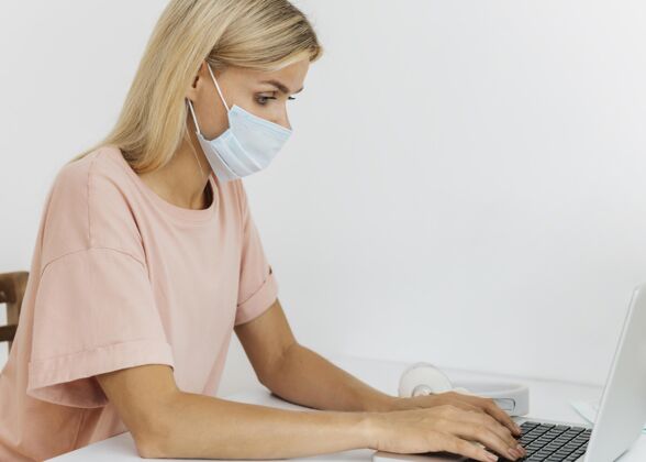 家庭大流行期间 戴着医用面罩在家工作的妇女的侧视图医疗冠状病毒流行病