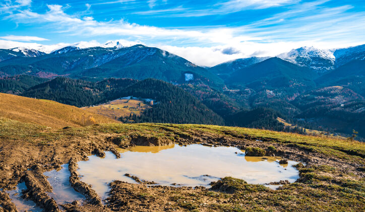 自然喀尔巴阡山脉的一条小径上 一个巨大的泥泞的水坑 上面满是恶心的泥土 映衬着美丽的秋山土壤阴天轨道