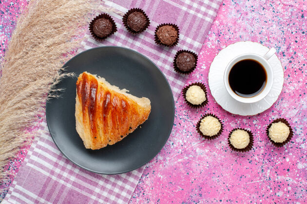 糕点粉红色表面上有一杯茶和巧克力糖果的糕点片俯视图烘焙盘子晚餐