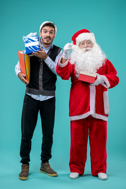 蓝色前视图圣诞老人与年轻的男性和礼物在蓝色地板度假雪新年假期圣诞节男人前面男性
