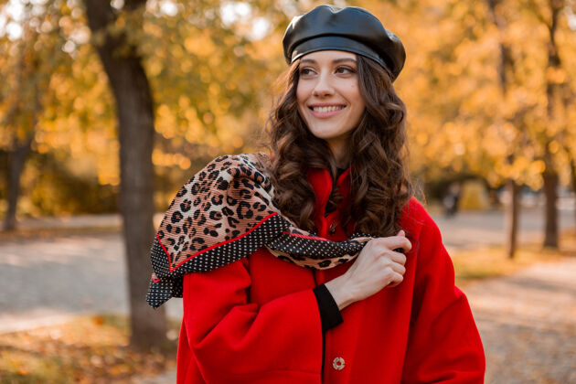 户外迷人时尚微笑的女人卷发漫步在公园穿着暖红色外套秋季时尚 街头风格 戴贝雷帽和豹纹围巾漂亮秋天户外