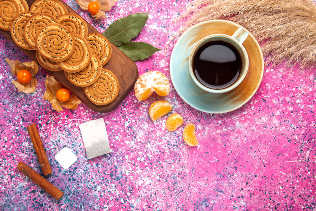 糖圆形甜饼的俯视图 粉色表面有一杯茶和橘子饮料圆的橘子