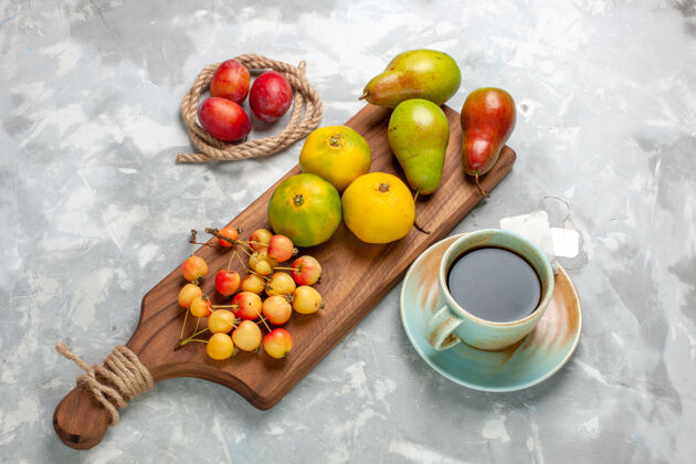 茶在浅白的桌子上俯瞰绿色的橘子和甜樱桃 李子 茶和梨苹果梨新鲜