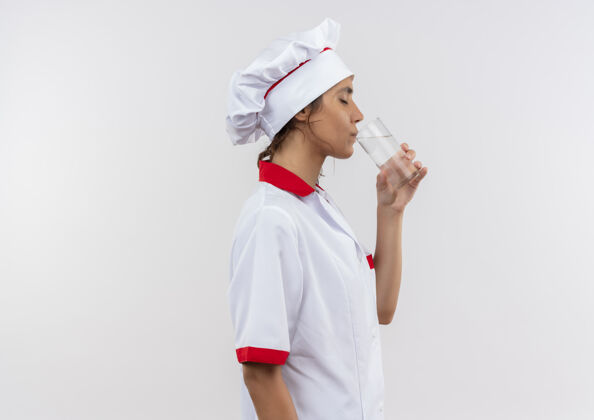厨师站在剖面图年轻的女厨师穿着厨师制服饮用水从玻璃复制空间厨师玻璃女性