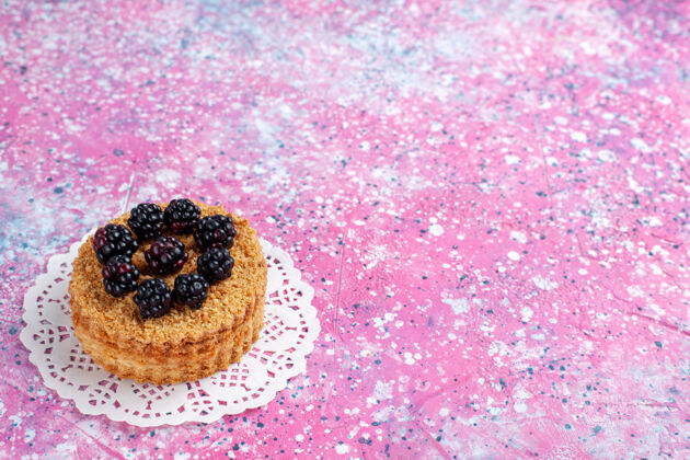 浅粉色正面近距离观看浅粉色背景上的小黑莓蛋糕关闭浆果前面