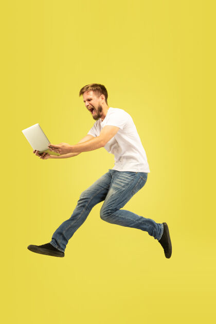 男性黄色背景上孤立的快乐跳跃人的全长肖像穿着休闲服的白人男模自由选择 灵感 人类情感概念在飞行中使用平板电脑选择成功办公室