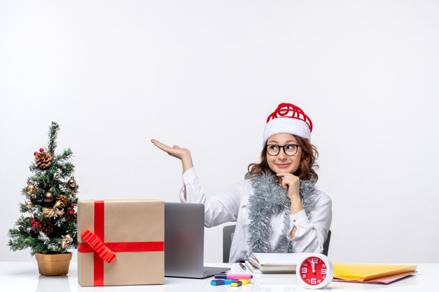 女士正面图：年轻的女工坐在她工作的地方 在白色的背景下思考圣诞节办公室坐着