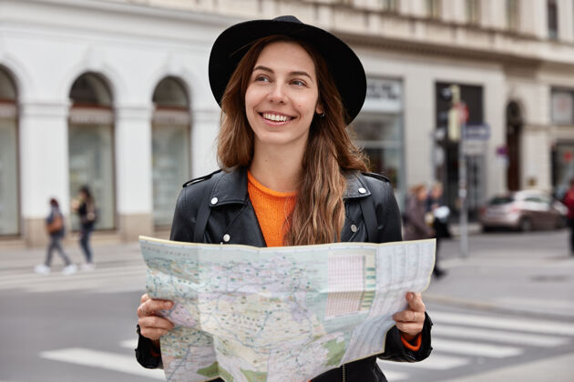 欧洲高兴的女人拿着纸质地图 游览城市 环顾四周 寻找新的目的地 戴着黑帽子学习快乐目的地