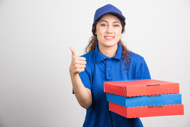 微笑披萨送货员拿着白色背景的披萨盒竖起大拇指用餐美味年轻人
