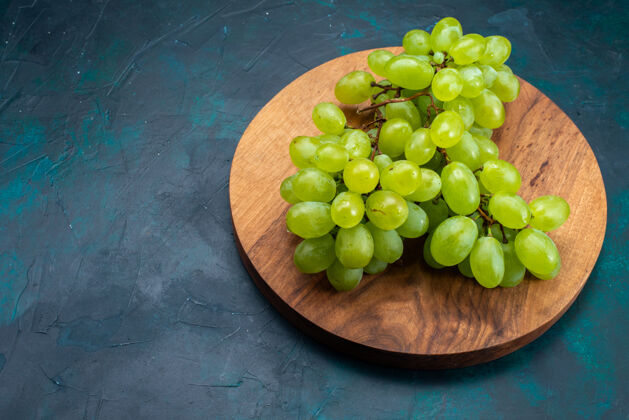 顶部在深蓝色的桌子上俯瞰新鲜的绿色葡萄 醇厚多汁的水果水果葡萄新鲜
