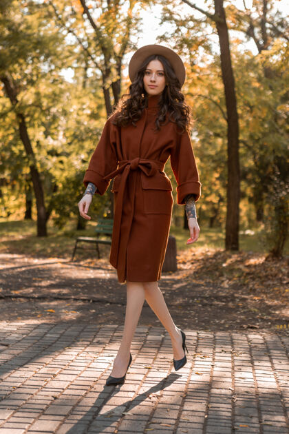魅力迷人时尚微笑的瘦身女子卷发漫步公园身着暖棕色外套 秋日时尚街头风欢快夹克配饰