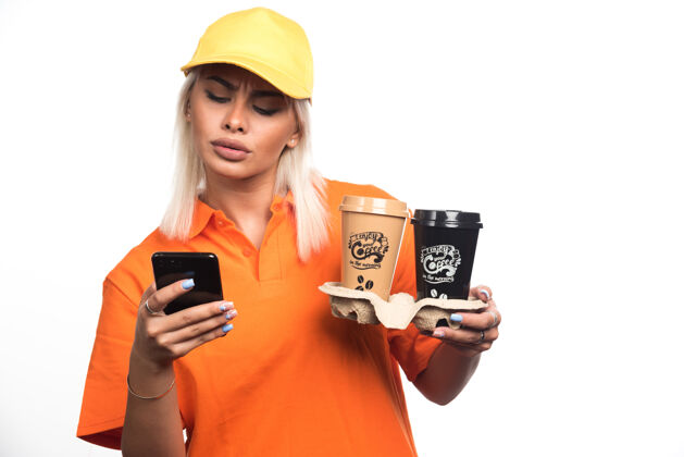 送货女信使手持两杯白色背景的咖啡 同时使用电话高质量的照片快递外卖女孩