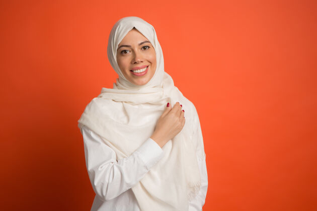 人戴着头巾的快乐阿拉伯女人微笑女孩的肖像 在红色工作室背景下摆姿势年轻感性的女人人类情感 面部表情概念正面视图阿拉伯亚洲人肖像