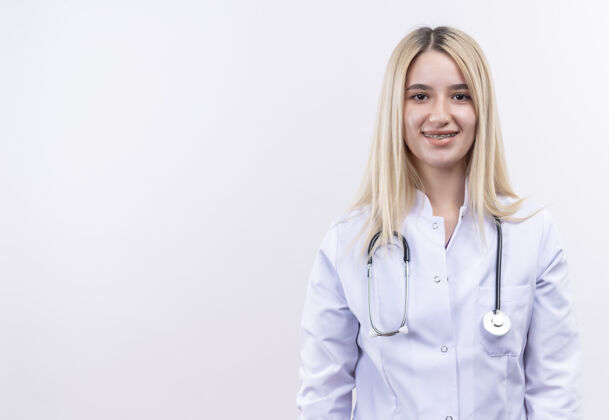 长袍微笑的医生年轻的金发女孩戴着听诊器和医用长袍戴着牙套在孤立的白色背景金发医疗医生