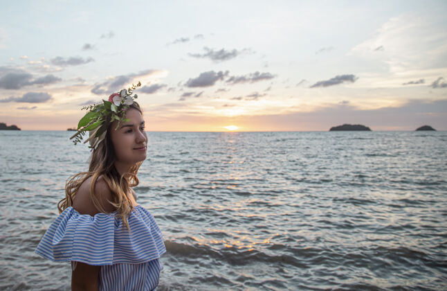 海洋日落时大海背景下一位头戴鲜花的年轻女子的肖像画日落夏天肖像