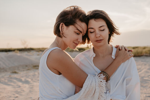 同性恋两个年轻女子在日落海滩上玩得很开心 男女同性恋爱情浪漫女人微笑女孩