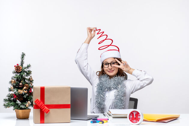 圣诞节正面图：年轻的女工坐在她工作的地方前面 背景是白色的微笑风景女人