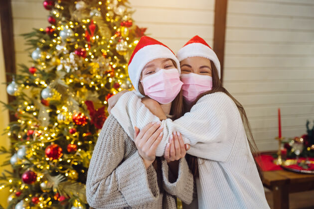 女人两个戴着防护面具的女孩看着镜头圣诞节期间冠状病毒 概念传统冠状病毒圣诞老人