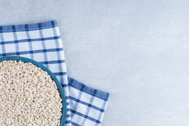 大米在折叠毛巾上放一个蓝色的小托盘 在大理石背景上装满了短粒米饭配料毛巾天然