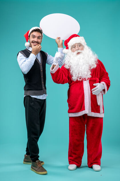 男人前视图圣诞老人与年轻男子谁持有白色标志蓝色地板圣诞新年假期雪的颜色圣诞老人男性前面