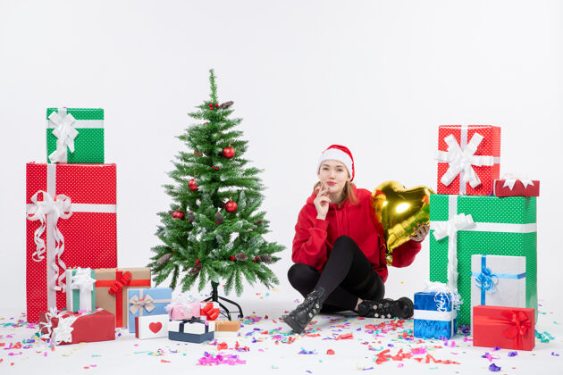 礼物前视图年轻女子围坐在一个白色的墙上拿着金色的心形礼物十二月情感礼物