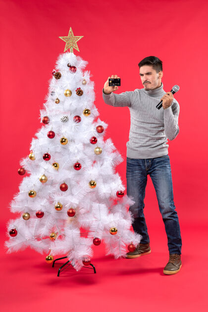 雪人圣诞气氛与骄傲的家伙站在装饰圣诞树附近 手持麦克风和电话心情红色圣诞