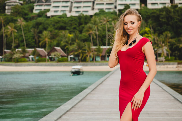 魅力年轻漂亮迷人的女人独自站在豪华度假酒店的码头上 暑假 红色长裙 金色头发 性感服装 热带沙滩 诱惑 性感 微笑风放松模特