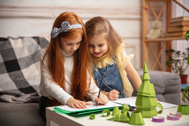 开始圣诞树两个孩子 女孩一起创造快乐的孩子为游戏或新年庆祝手工玩具小白种人模型快乐的童年 庆祝准备家庭礼物圣诞节
