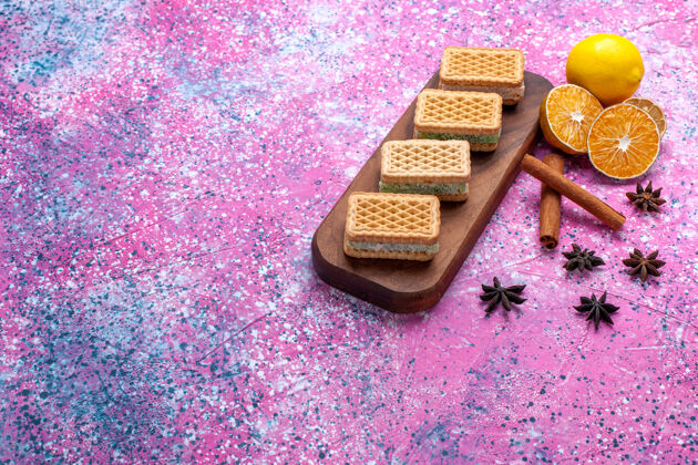 正面浅粉色书桌上有水果奶油填充的华夫饼干三明治糖果水果饼干