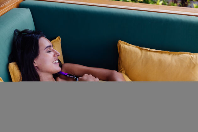 热带美丽苗条的正面女性的肖像 躺在家里的枕头上 躺在夏日的户外沙发上 享受独处的时光平静享受休息