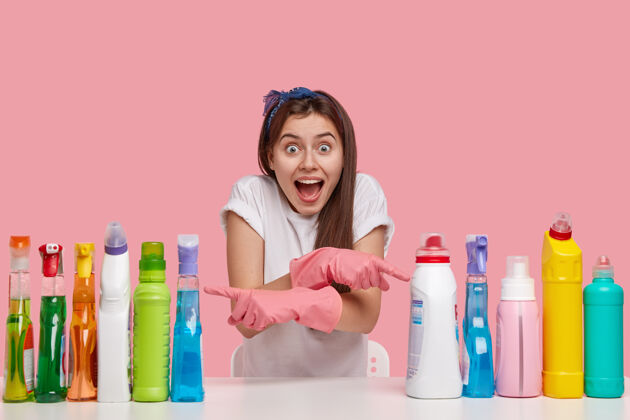 服务快乐的欧洲女士的室内镜头 表情喜出望外 张嘴 交叉手 在洗涤剂的两边指示T恤高兴单独