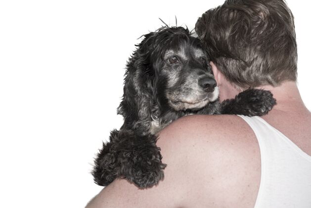轮廓一个男人抱着一只黑狗的特写镜头人拥抱小狗