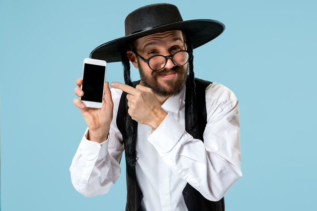 犹太人一个年轻的东正教犹太男子的肖像和手机在工作室宗教胡须智能手机