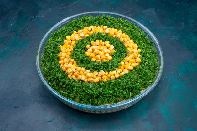 圆形在深蓝色背景的圆形玻璃盘中放上半顶面绿叶沙拉和玉米玉米蔬菜美味